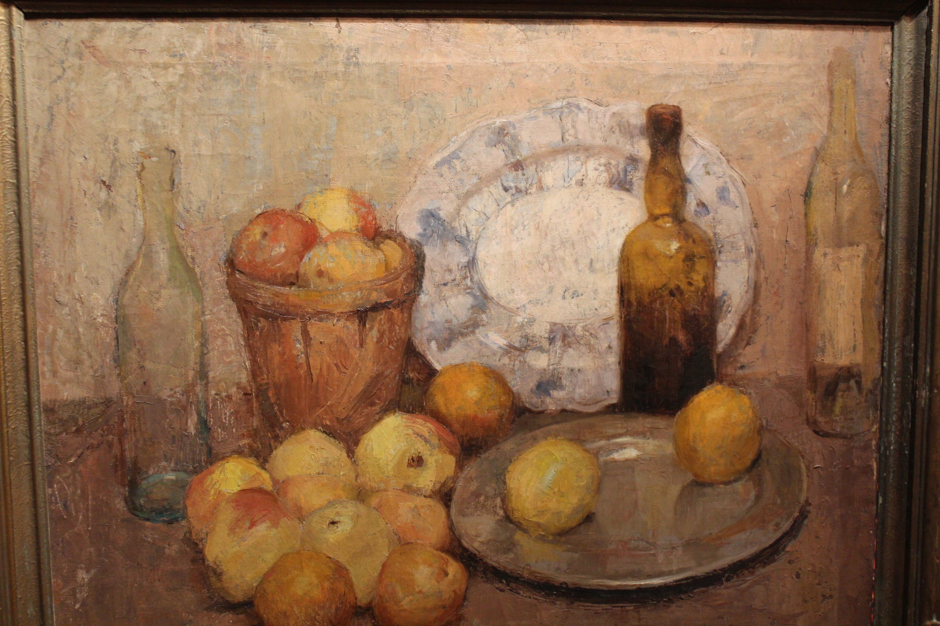 A painting featuring a still life with apples, bowls, and plates, framed in a carved wooden frame.