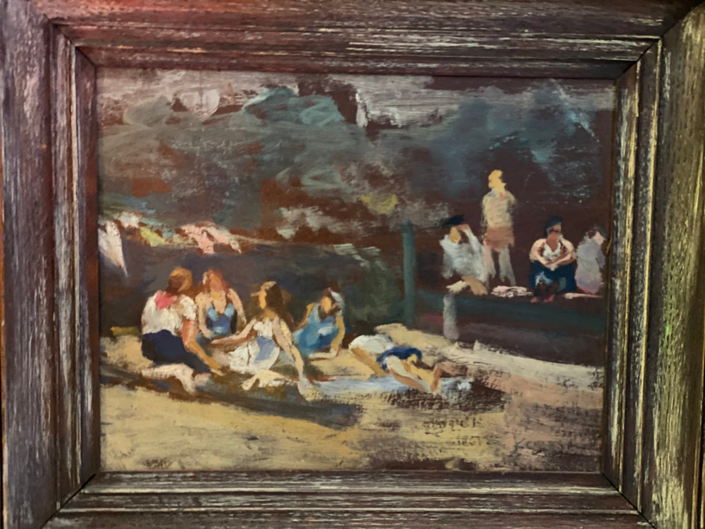 A framed artwork depicting a beach scene with figures swimming and relaxing on the sand.