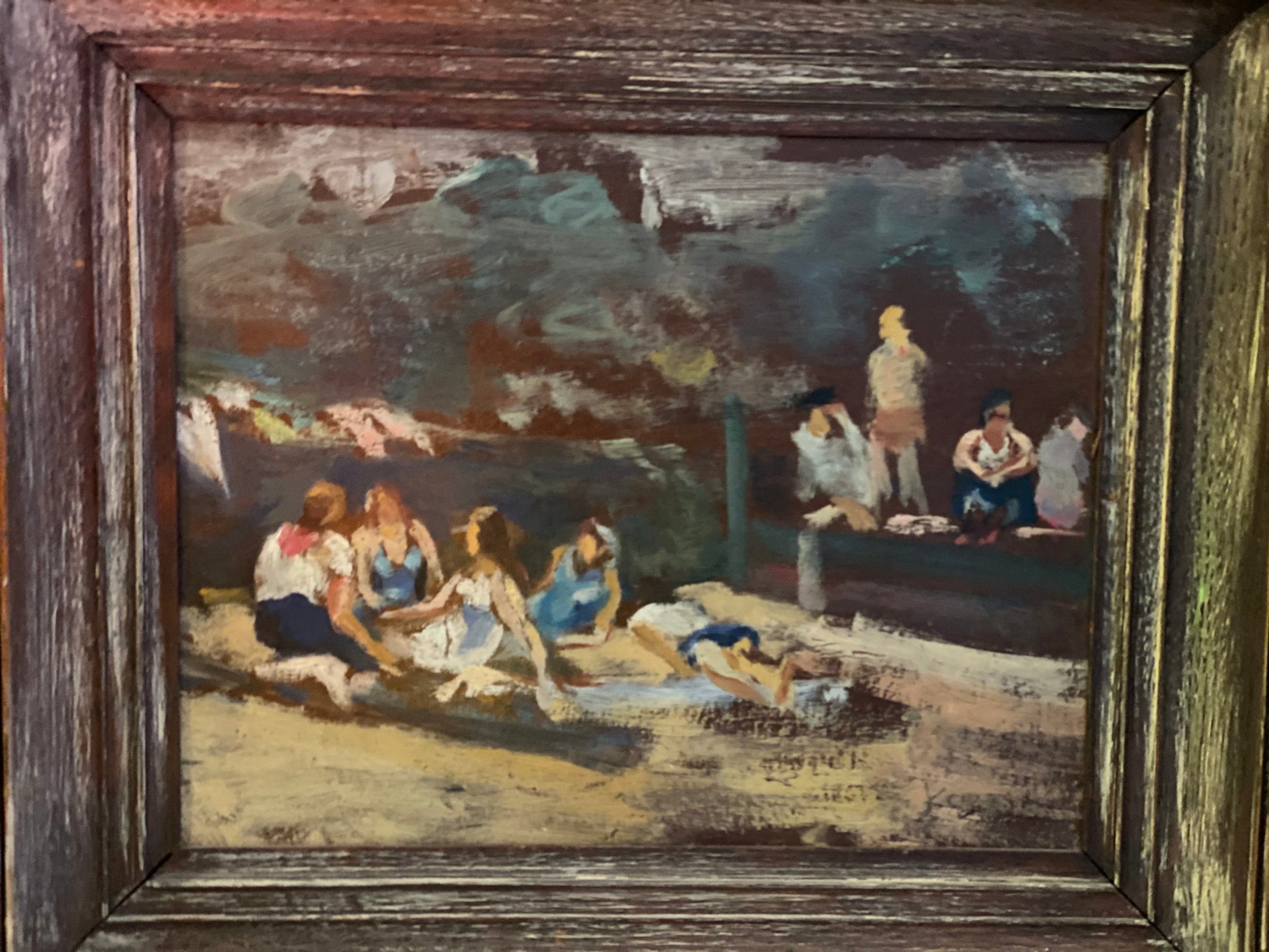 A framed artwork depicting a beach scene with figures swimming and relaxing on the sand.
