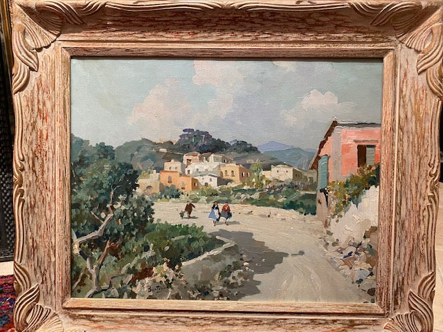 A framed impressionist painting depicting a village scene with a carved wooden European frame.
