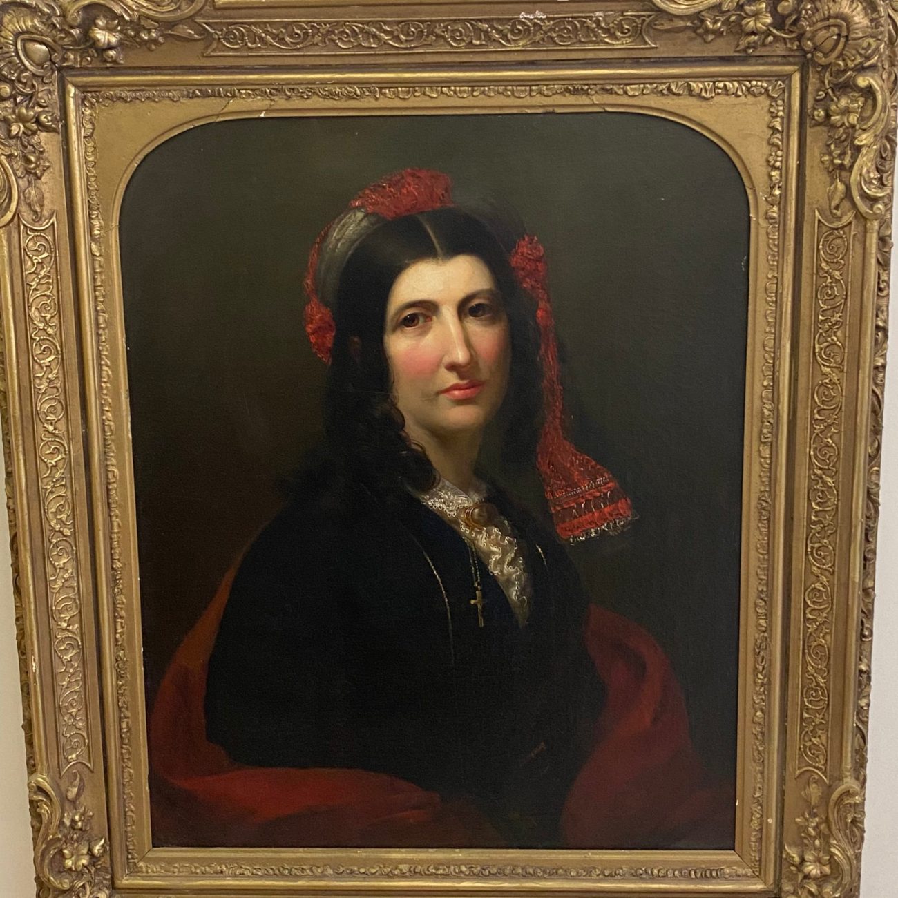 19th century French portrait of George Sand, showing a woman with a red flower in her hair, dressed in a black and red outfit, framed in an ornate gold frame.