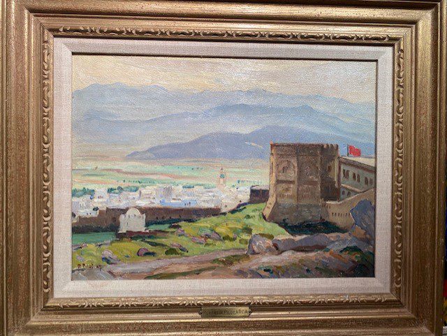 A framed artwork depicting a scenic view of a cityscape with mountains in the background, signed and dated by the artist.